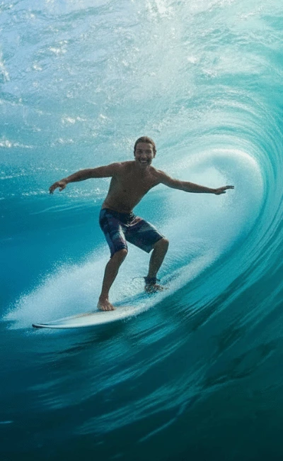 Surfer crouched low inside the curl of a hollow turquoise wave
